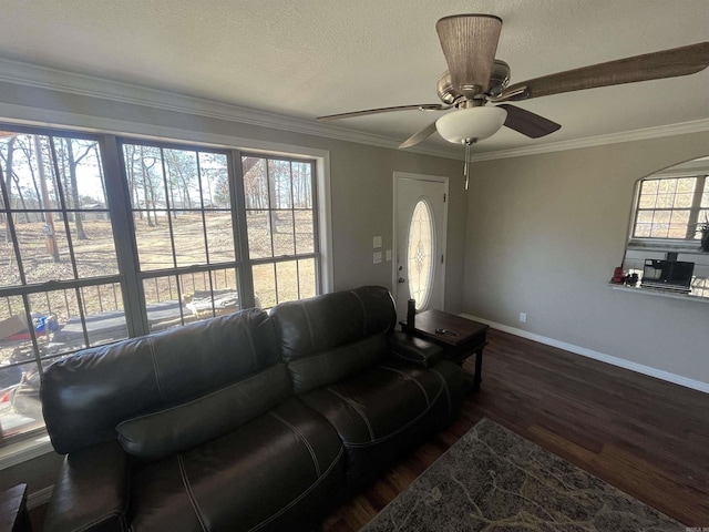 living area with baseboards, ceiling fan, dark wood-type flooring, and crown molding