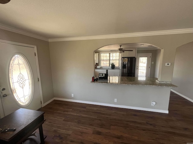 entrance foyer featuring arched walkways, dark wood-style flooring, a ceiling fan, baseboards, and ornamental molding