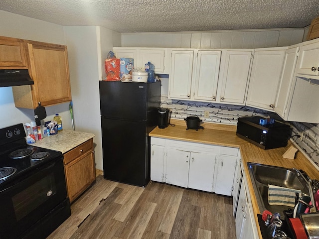 kitchen featuring a textured ceiling, under cabinet range hood, wood finished floors, light countertops, and black appliances