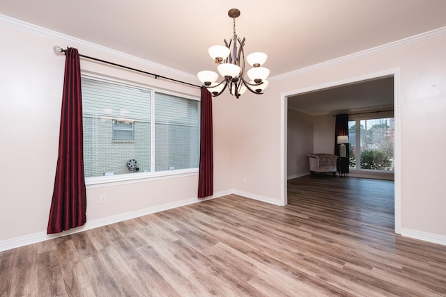 empty room with ornamental molding, wood finished floors, and baseboards