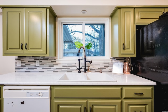 kitchen with a sink, green cabinets, light countertops, backsplash, and dishwasher