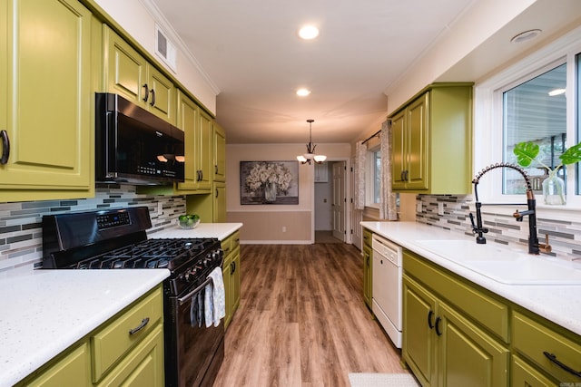 kitchen featuring green cabinetry, a sink, light countertops, black appliances, and crown molding