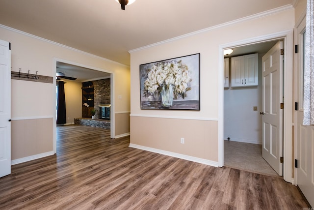 unfurnished room with baseboards, a fireplace, wood finished floors, and crown molding