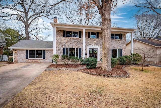 neoclassical / greek revival house featuring brick siding, a chimney, and a front lawn