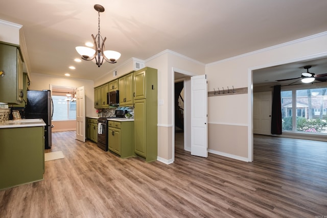 kitchen featuring black gas range, tasteful backsplash, light countertops, light wood-style floors, and green cabinets