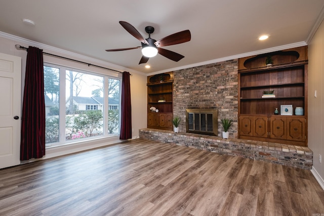 unfurnished living room with ornamental molding, a brick fireplace, and wood finished floors