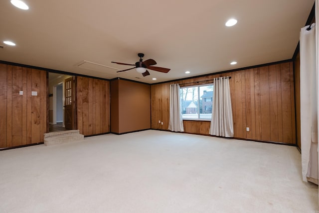 spare room featuring attic access, light carpet, and wooden walls