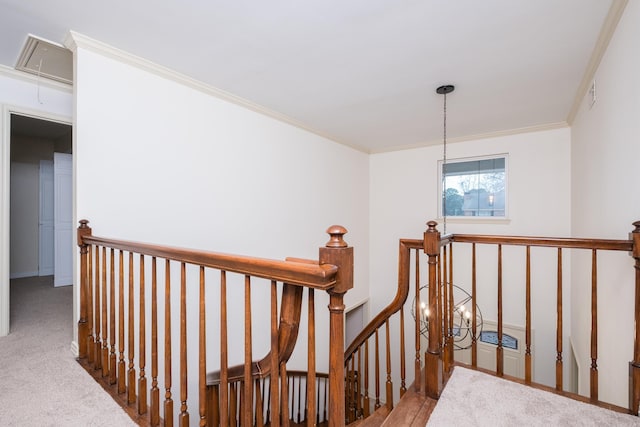 corridor featuring attic access, visible vents, ornamental molding, carpet, and an upstairs landing