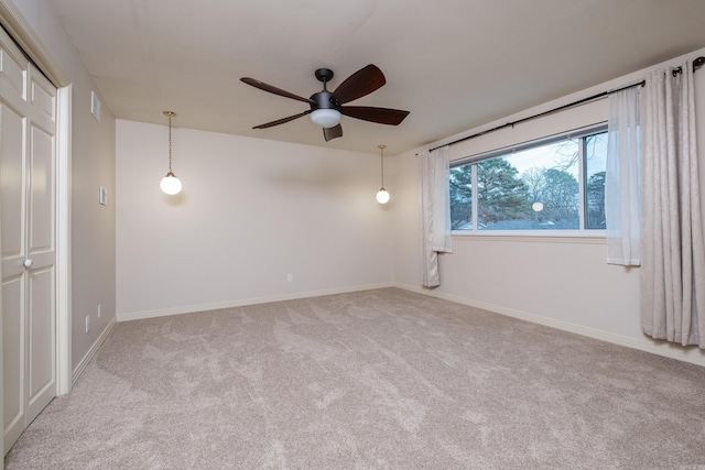 carpeted spare room featuring ceiling fan, visible vents, and baseboards