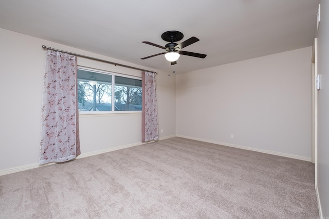 carpeted spare room featuring a ceiling fan and baseboards