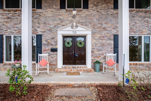 property entrance featuring brick siding and a porch