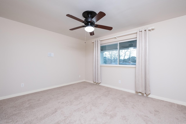 carpeted spare room with ceiling fan and baseboards