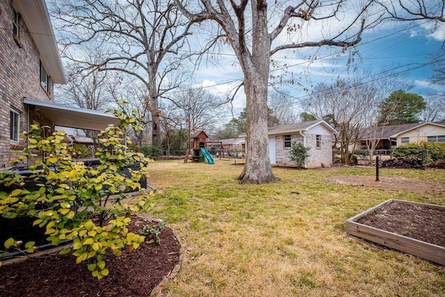 view of yard featuring a garden, a playground, an outdoor structure, and fence