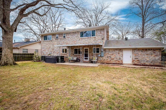 back of property featuring brick siding, a patio, a lawn, a hot tub, and fence