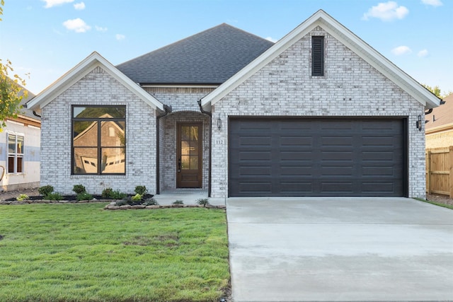 french provincial home featuring driveway, a garage, brick siding, roof with shingles, and a front yard