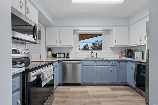 kitchen featuring wine cooler, white cabinetry, stainless steel appliances, and a sink