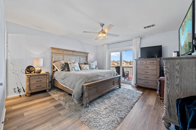 bedroom featuring access to exterior, a ceiling fan, visible vents, and wood finished floors