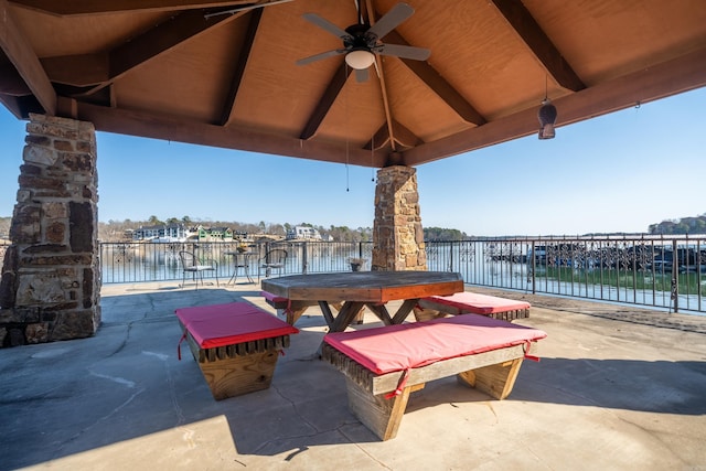 view of patio with outdoor dining area, a water view, and a ceiling fan