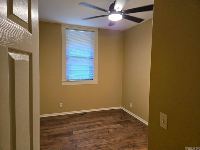 spare room featuring visible vents, dark wood-style flooring, a ceiling fan, and baseboards