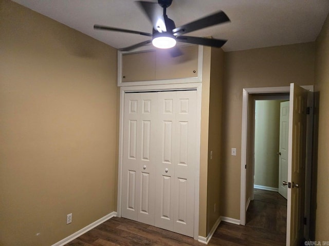 unfurnished bedroom featuring dark wood-type flooring, a closet, baseboards, and a ceiling fan