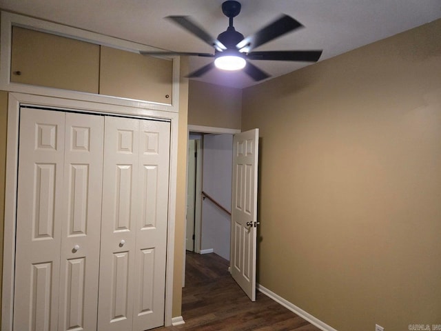 unfurnished bedroom featuring ceiling fan, dark wood-type flooring, a closet, and baseboards