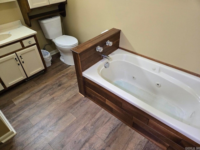 full bathroom with vanity, a jetted tub, wood finished floors, and toilet