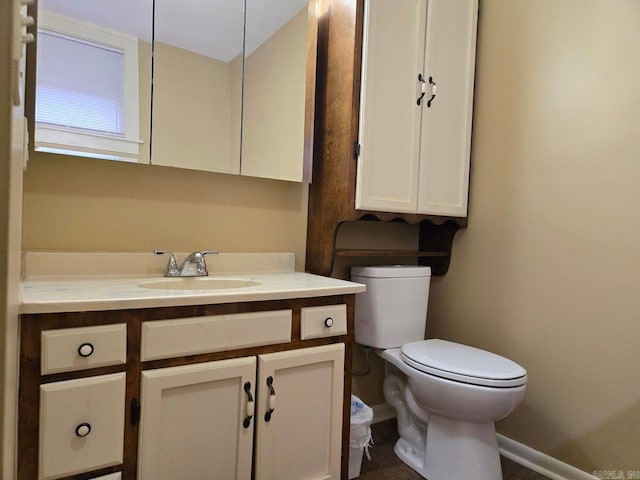 bathroom featuring toilet, baseboards, and vanity