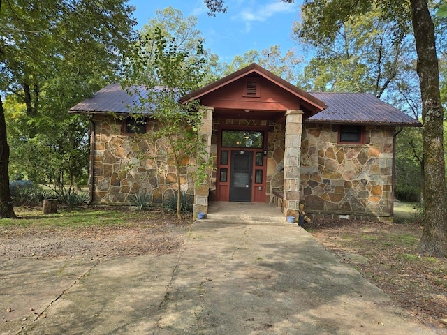 view of front of home featuring stone siding and metal roof