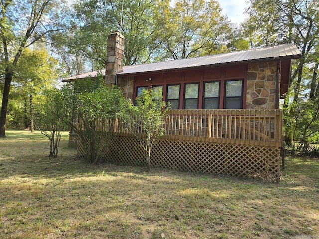 rear view of house with metal roof, stone siding, a deck, and a chimney