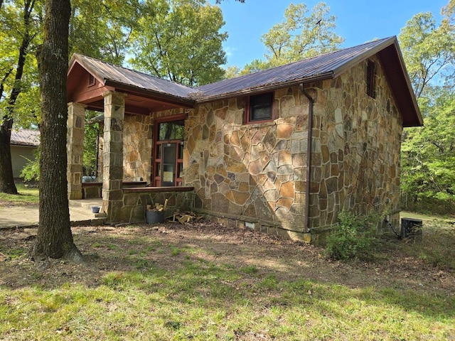 view of property exterior featuring stone siding and metal roof