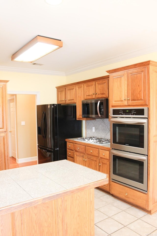 kitchen featuring light tile patterned floors, stainless steel appliances, visible vents, ornamental molding, and tasteful backsplash