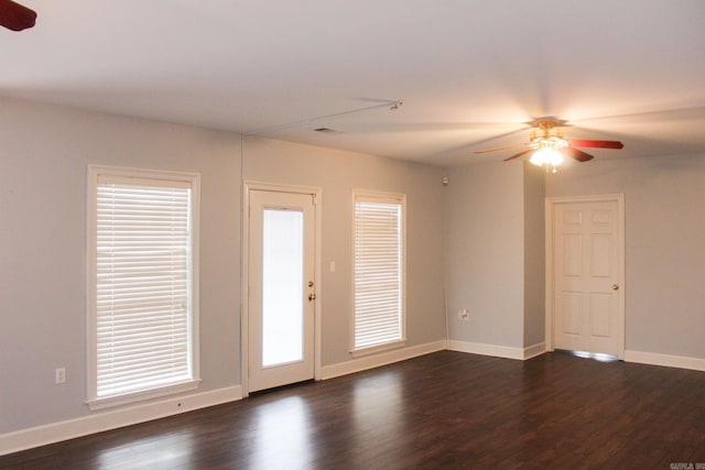 spare room with dark wood-style floors, visible vents, a ceiling fan, and baseboards