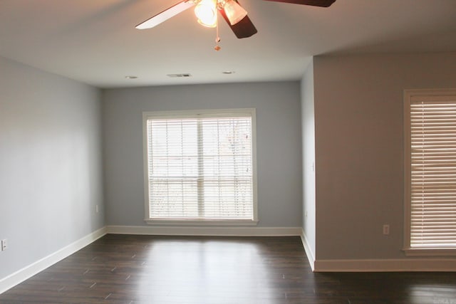 empty room featuring a ceiling fan, dark wood-style flooring, visible vents, and baseboards