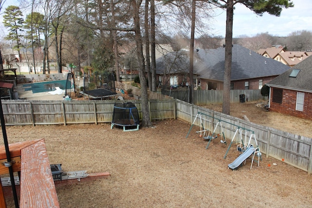 view of yard with a fenced backyard, a trampoline, and a playground