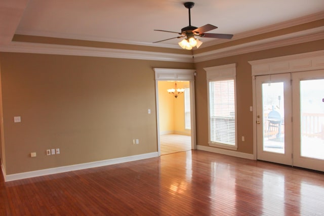 unfurnished room with crown molding, wood finished floors, a raised ceiling, and a healthy amount of sunlight