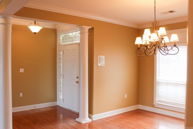 foyer featuring ornamental molding, light wood finished floors, and ornate columns