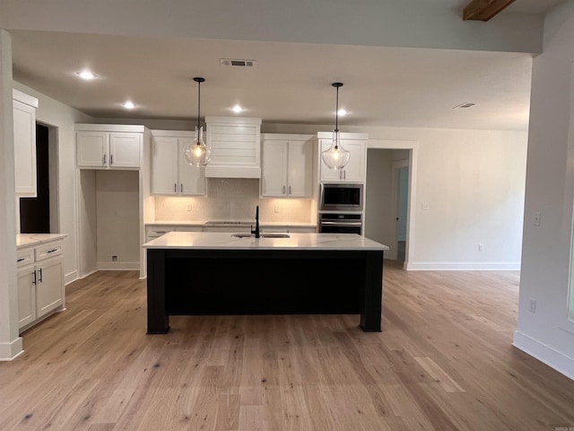 kitchen with stainless steel appliances, visible vents, backsplash, a sink, and premium range hood