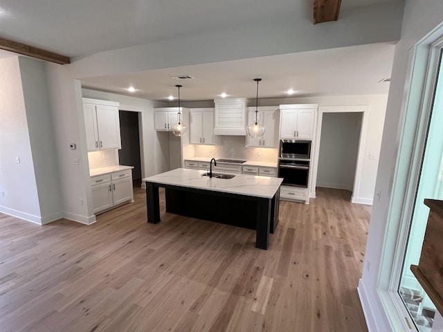 kitchen featuring light wood-style flooring, stainless steel appliances, a sink, white cabinetry, and beam ceiling