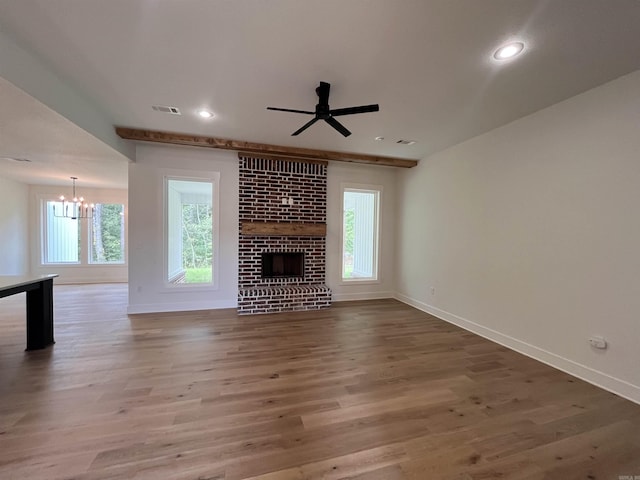 unfurnished living room with visible vents, a fireplace, baseboards, and wood finished floors