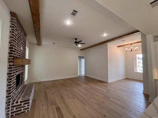 unfurnished living room featuring light wood finished floors, a fireplace, visible vents, and ceiling fan with notable chandelier