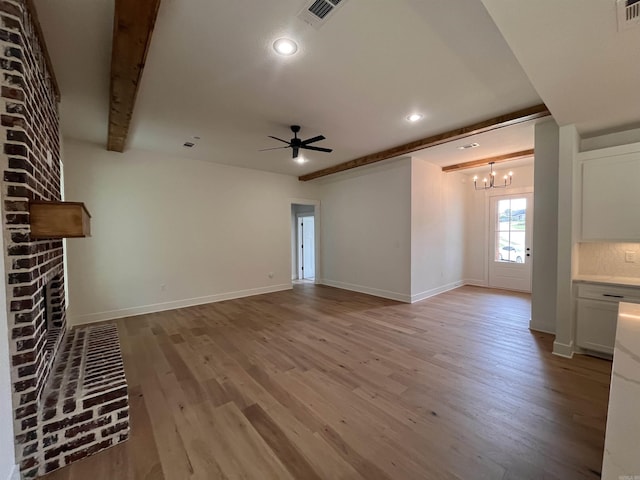 unfurnished living room with light wood-type flooring, a fireplace, visible vents, and beamed ceiling