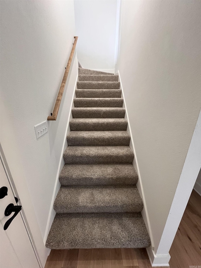 stairs with wood finished floors and baseboards