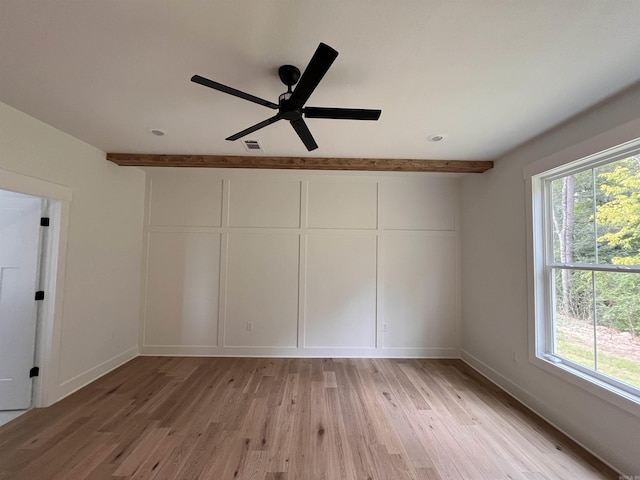 empty room with beamed ceiling, light wood-type flooring, and baseboards