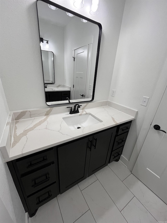 bathroom with marble finish floor and vanity