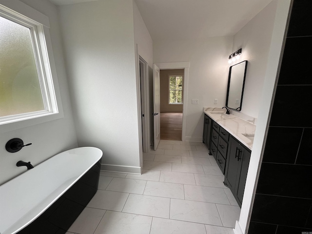 full bath with double vanity, baseboards, and a freestanding bath