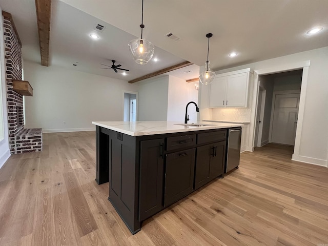 kitchen with light wood-style flooring, a sink, white cabinetry, stainless steel dishwasher, and an island with sink