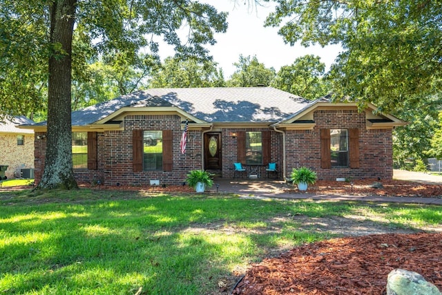 ranch-style house with a front lawn, a shingled roof, and brick siding