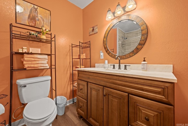 bathroom featuring baseboards, vanity, toilet, and wood finished floors