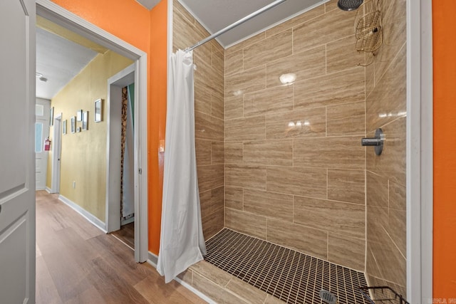 bathroom featuring tiled shower, wood finished floors, and baseboards