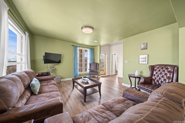 living area featuring visible vents, plenty of natural light, baseboards, and wood finished floors